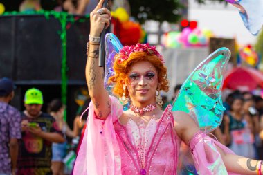 Gülümseyen trans bir kadın, pembe giyinmiş, Goiania şehrindeki LGBT Onur Yürüyüşü sırasında sokakta dans ediyor..