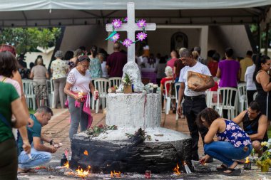 Mezarlıkta bir sürü insan dua ediyor ve büyük beton bir haçın etrafında mum yakıyor. Tüm Ruhlar Günü.