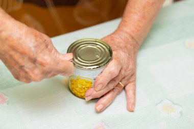 Mutfak masasında konserve mısır konservesi açan bir aşçının ellerini kapat..