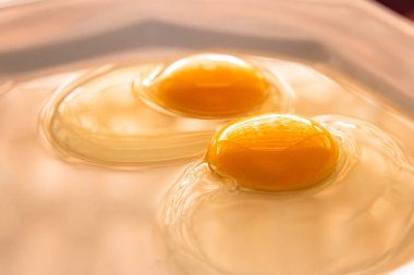 Beyaz bir porselen tabakta iki çiğ yumurta..