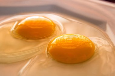Beyaz bir porselen tabakta iki çiğ yumurta..