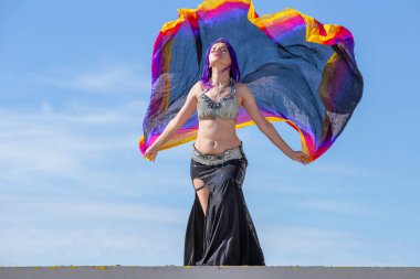 Arka planda mavi gökyüzü olan, peçe takan genç bir kadın..