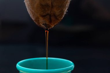 Kahvenin ayrıntıları siyah arka planı olan yeşil bir diş minesi bardağına dökülüyor..