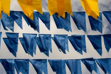 Arka planda bulutlu bir gökyüzü olan mavi ve sarı flamalarla dolu çamaşır ipleri. Kare dansı için dekorasyon.