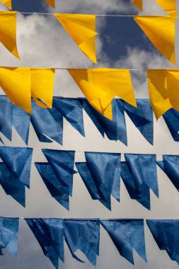 Arka planda bulutlu bir gökyüzü olan mavi ve sarı flamalarla dolu çamaşır ipleri. Kare dansı için dekorasyon.