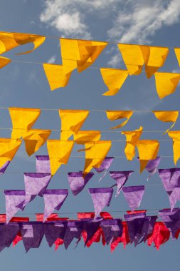Arka planda mavi gökyüzü olan sarı, mor ve kırmızı bayraklar. Brezilya Haziran festivali arka planı.
