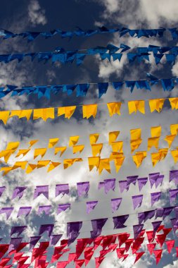 Arka planda bulutlar ve gökyüzü olan birçok renkli bayraklı çamaşır ipleri. Kare dansı için dekorasyon - tipik bir Brezilyalı partisi.