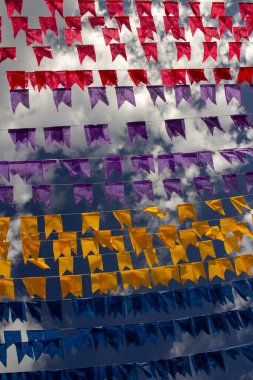 Rüzgarda dalgalanan birçok bayrak, gökyüzü ve arka planda bulutlar olan birkaç çamaşır ipi. Kare dansı için dekorasyon, tipik bir Brezilya partisi..