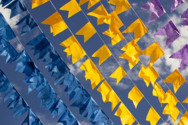 Renkli flama çizgileri, mavi, sarı ve mor, arka planda mavi bir gökyüzü. Rüzgarda sallanıyor.