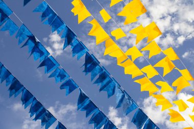 Renkli flama çizgileri, mavi, sarı ve mor, arka planda mavi bir gökyüzü. Rüzgarda sallanıyor.