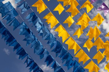 Renkli flama çizgileri, mavi, sarı ve mor, arka planda mavi bir gökyüzü. Rüzgarda sallanıyor.