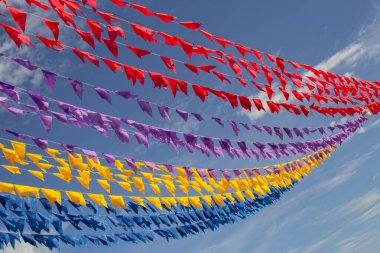 Renkli dekoratif bayraklı, arka planda mavi gökyüzü olan birçok çamaşır ipi. Haziran festivali.