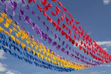 Renkli dekoratif bayraklı, arka planda mavi gökyüzü olan birçok çamaşır ipi. Haziran festivali.