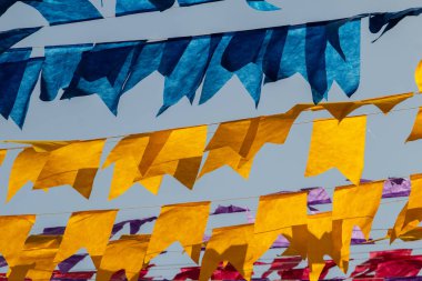 Arka planda bulutlu bir gökyüzü olan mavi ve sarı flamalarla dolu çamaşır ipleri. Kare dansı için dekorasyon.