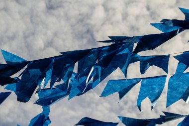 Rüzgarda sallanan bir sürü mavi flamalı ve arka planda gökyüzü olan çamaşır ipleri..