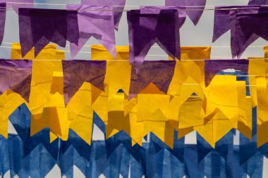 Üzerlerinde renkli flamalar asılı bazı ipler. Tam kare. Arka planda mavi gökyüzü.