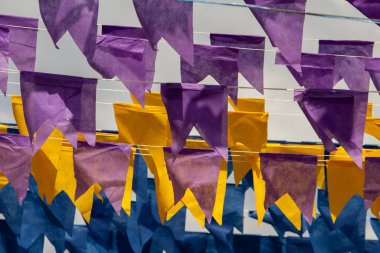 Üzerlerinde renkli flamalar asılı bazı ipler. Tam kare. Arka planda mavi gökyüzü.