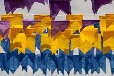 Üzerlerinde renkli flamalar asılı bazı ipler. Tam kare. Arka planda mavi gökyüzü.