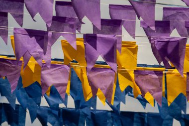 Üzerlerinde renkli flamalar asılı bazı ipler. Tam kare. Arka planda mavi gökyüzü.