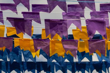 Üzerlerinde renkli flamalar asılı bazı ipler. Tam kare. Arka planda mavi gökyüzü.