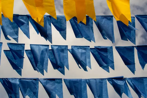 Arka planda bulutlu bir gökyüzü olan mavi ve sarı flamalarla dolu çamaşır ipleri. Kare dansı için dekorasyon.