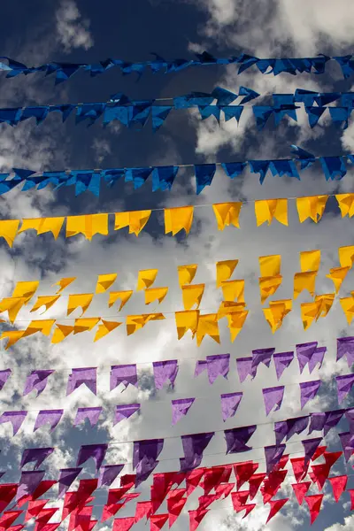 Arka planda bulutlar ve gökyüzü olan birçok renkli bayraklı çamaşır ipleri. Kare dansı için dekorasyon - tipik bir Brezilyalı partisi.