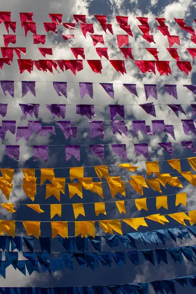 Arka planda bulutlar ve gökyüzü olan birçok renkli bayraklı çamaşır ipleri. Kare dansı için dekorasyon - tipik bir Brezilyalı partisi.