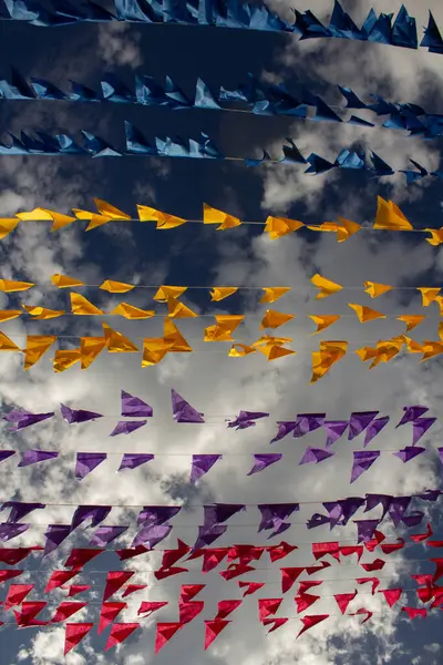 Arka planda bulutlar ve gökyüzü olan birçok renkli bayraklı çamaşır ipleri. Kare dansı için dekorasyon - tipik bir Brezilyalı partisi.