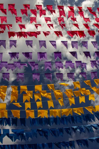 Arka planda bulutlar ve gökyüzü olan birçok renkli bayraklı çamaşır ipleri. Kare dansı için dekorasyon - tipik bir Brezilyalı partisi.