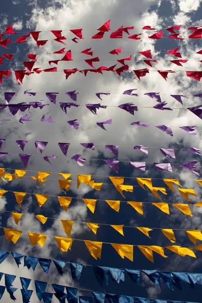 Arka planda bulutlar ve gökyüzü olan birçok renkli bayraklı çamaşır ipleri. Kare dansı için dekorasyon - tipik bir Brezilyalı partisi.