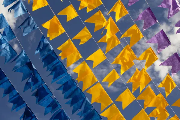 Renkli flama çizgileri, mavi, sarı ve mor, arka planda mavi bir gökyüzü. Rüzgarda sallanıyor.