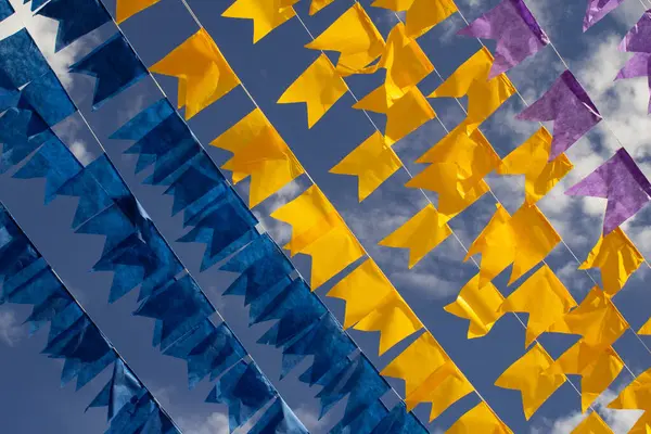 Renkli flama çizgileri, mavi, sarı ve mor, arka planda mavi bir gökyüzü. Rüzgarda sallanıyor.