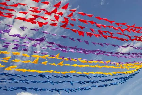Renkli dekoratif bayraklı, arka planda mavi gökyüzü olan birçok çamaşır ipi. Haziran festivali.