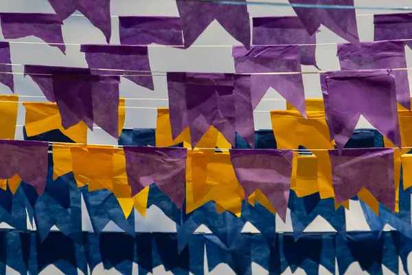 Üzerlerinde renkli flamalar asılı bazı ipler. Tam kare. Arka planda mavi gökyüzü.