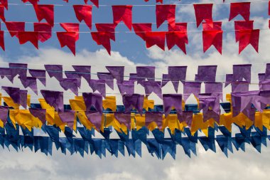 Arkaplanda mavi gökyüzü asılı renkli flamalar olan dizelere odaklan.