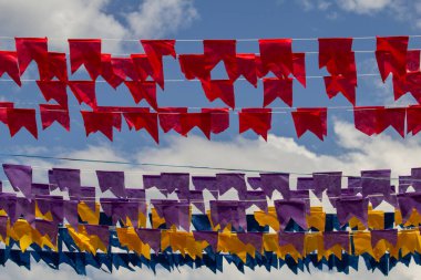 Arkaplanda mavi gökyüzü asılı renkli flamalar olan dizelere odaklan.