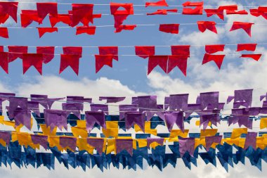 Arkaplanda mavi gökyüzü asılı renkli flamalar olan dizelere odaklan.