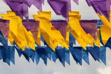 Üzerlerinde renkli flamalar asılı bazı ipler. Tam kare. Arka planda mavi gökyüzü.