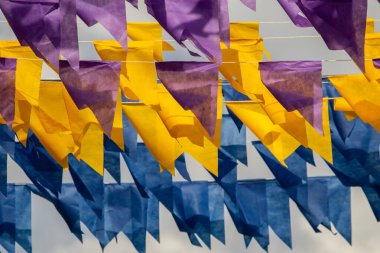 Üzerlerinde renkli flamalar asılı bazı ipler. Tam kare. Arka planda mavi gökyüzü.