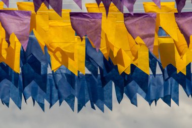 Üzerlerinde renkli flamalar asılı bazı ipler. Tam kare. Arka planda mavi gökyüzü.