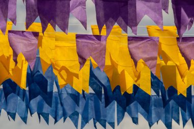 Üzerlerinde renkli flamalar asılı bazı ipler. Tam kare. Arka planda mavi gökyüzü.