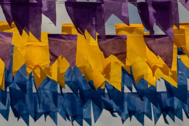 Üzerlerinde renkli flamalar asılı bazı ipler. Tam kare. Arka planda mavi gökyüzü.