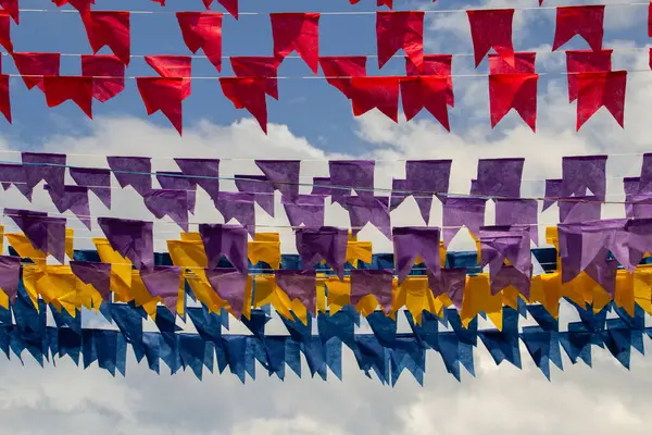 Arkaplanda mavi gökyüzü asılı renkli flamalar olan dizelere odaklan.