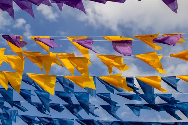 Arkaplanda rüzgarda sallanan ve gökyüzünde sallanan birçok renkli bayraklı dizgi çizgilerinin görüntüsü.