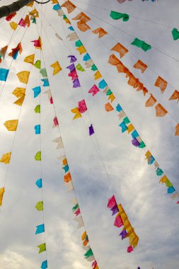 Arka planda bulutlu bir gökyüzü ile asılı renkli flama ipleri. Kare dansı için dekorasyon - tipik bir Brezilyalı partisi.