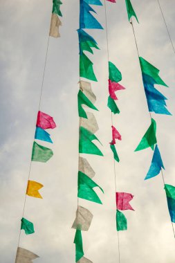Arka planda bulutlu bir gökyüzü ile asılı renkli flama ipleri. Kare dansı için dekorasyon - tipik bir Brezilyalı partisi.