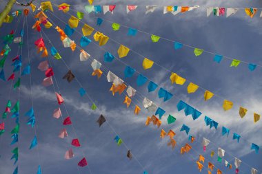 Renkli flamalar sallanan, rüzgarda sallanan, arka planda mavi bir gökyüzü olan bir dizi ip. Kare dans için dekorasyon - tipik bir Brezilya