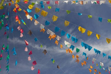 Renkli flamalar sallanan, rüzgarda sallanan, arka planda mavi bir gökyüzü olan bir dizi ip. Kare dans için dekorasyon - tipik bir Brezilya