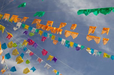 Renkli flamalar sallanan, rüzgarda sallanan, arka planda mavi bir gökyüzü olan bir dizi ip. Kare dans için dekorasyon - tipik bir Brezilya