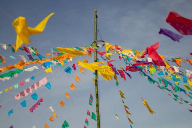 Renkli flamalar sallanan, rüzgarda sallanan, arka planda mavi bir gökyüzü olan bir dizi ip. Kare dansı ve Festa Junina için dekorasyon -